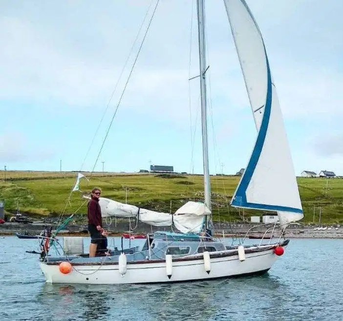 a man is standing on a sailboat in the water.