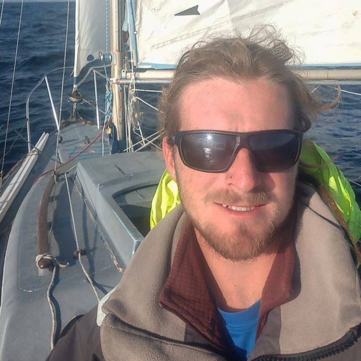 a man in sunglasses is taking a selfie on a sailboat.