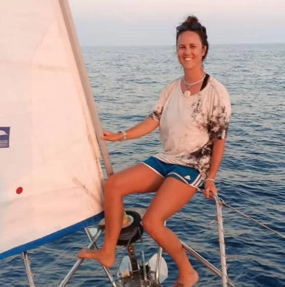 a woman sitting on the bow of a sailboat.