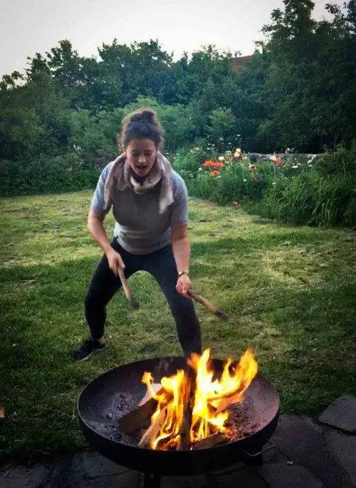 a woman is playing with a fire pit in a yard.