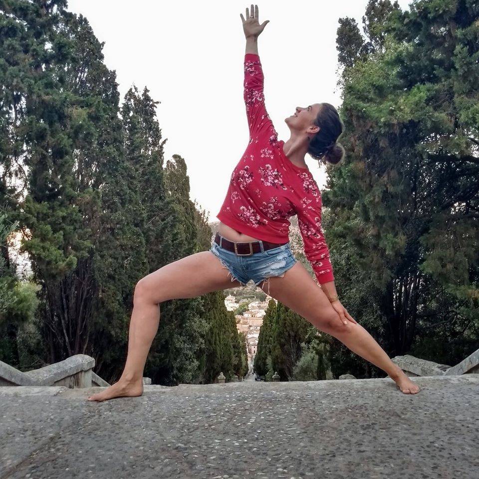 a woman doing a yoga pose on a stone wall.