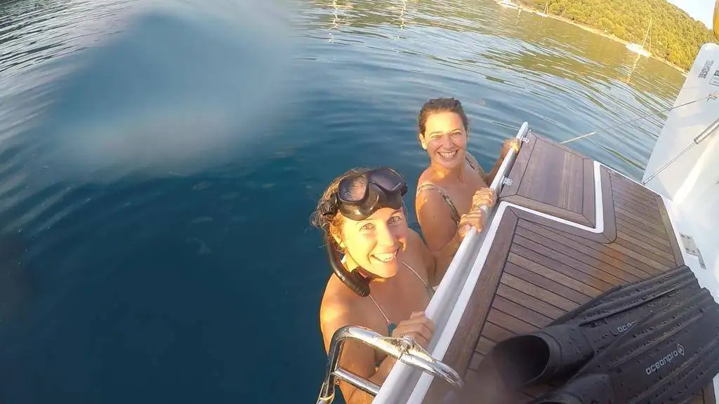 two women on a boat smiling at the camera.