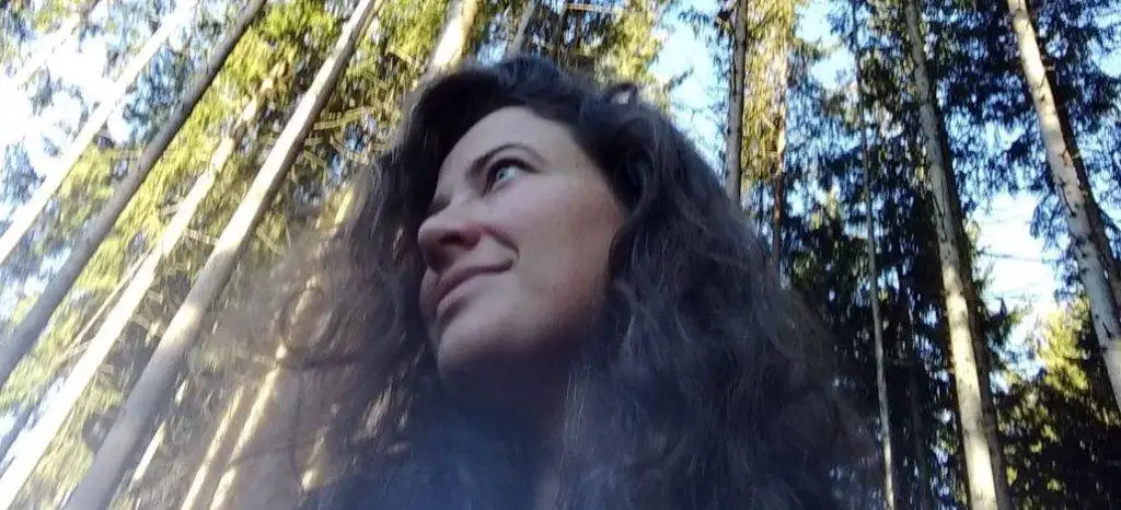 a woman is standing in a forest.
