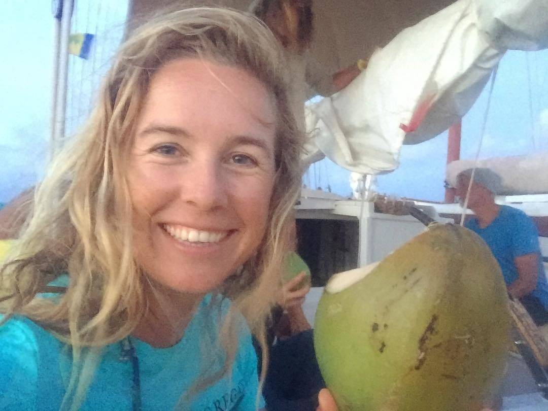 a woman holding a coconut on a boat.