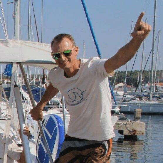a man on a sailboat waving his hands in the air.