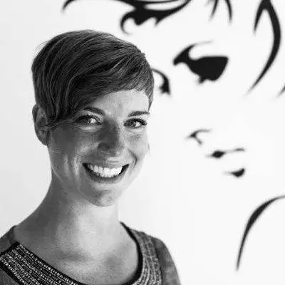 a black and white photo of a woman smiling in front of a wall.