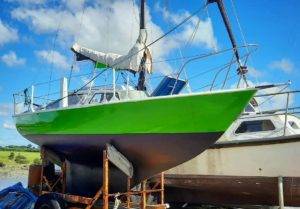 a green and black sailboat is sitting on a trailer.