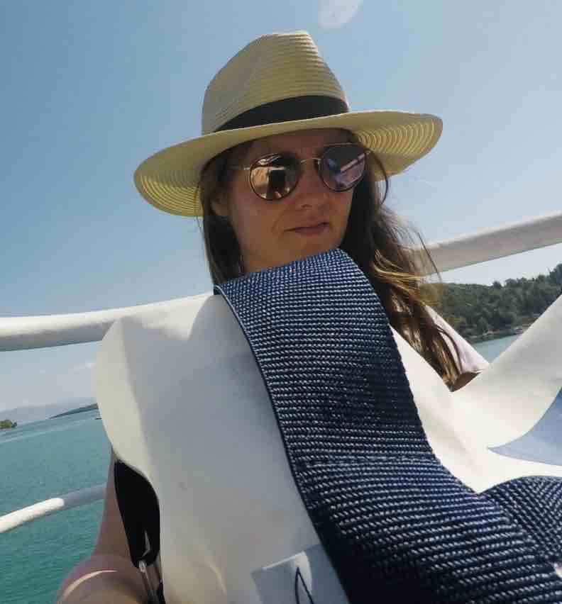 a woman wearing a hat and sunglasses on a boat.