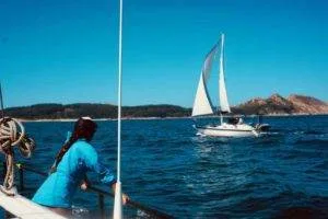 a woman is standing on the bow of a sailboat in the ocean.