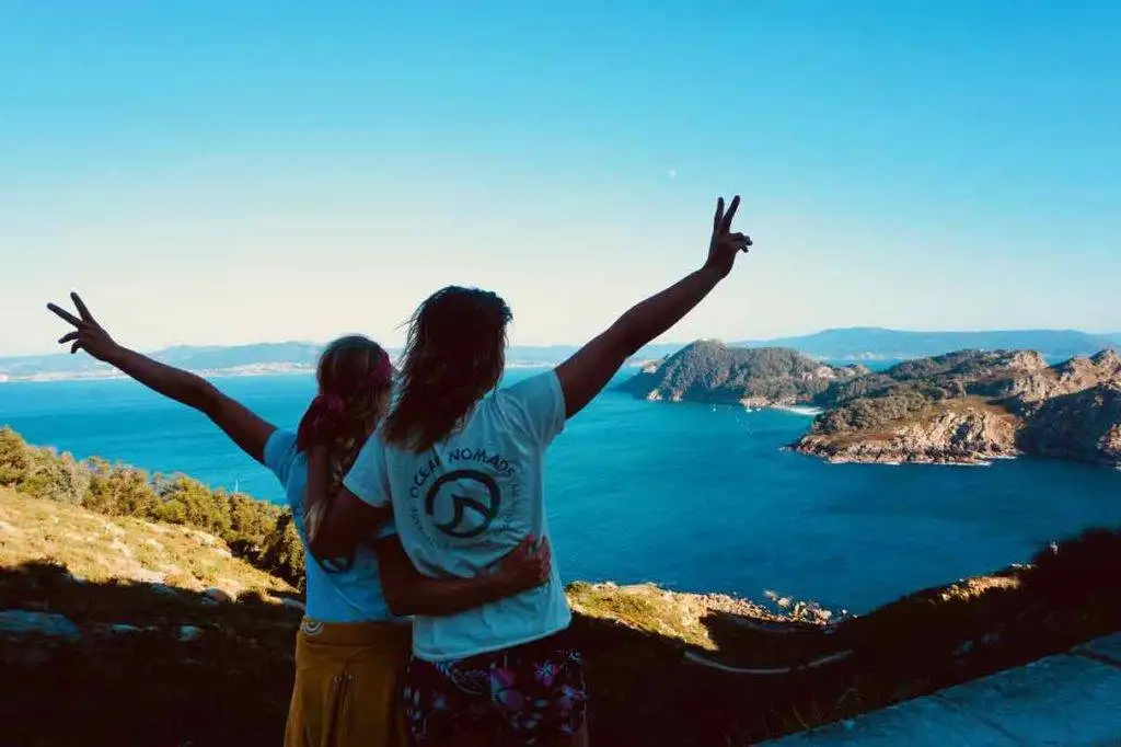 two women standing on a cliff overlooking the ocean.