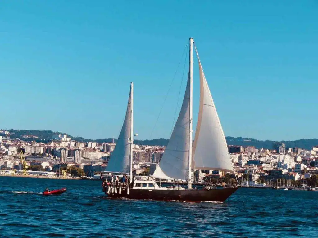 a sailboat in the water with a city in the background.