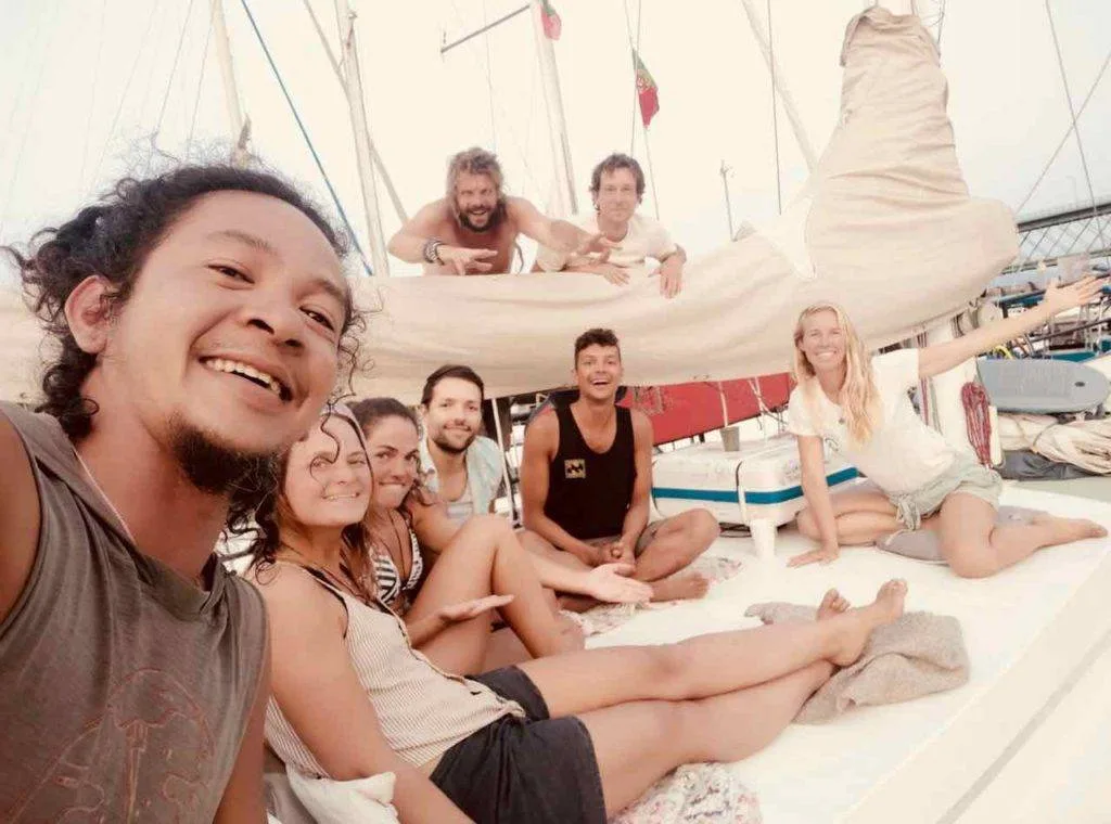 a group of people on a sailboat posing for a photo.