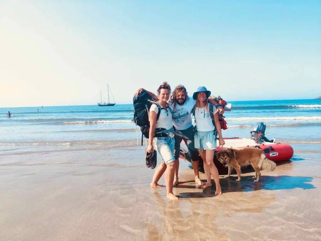 a group of people standing on the beach with a dog.