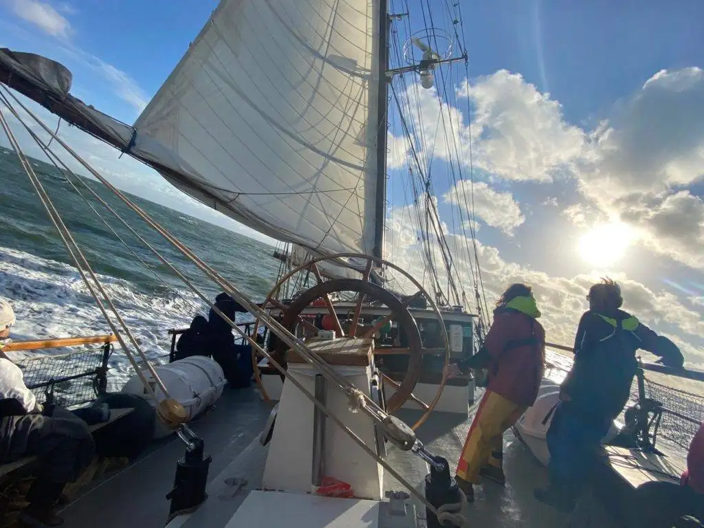 a group of people standing on the deck of a sailboat.