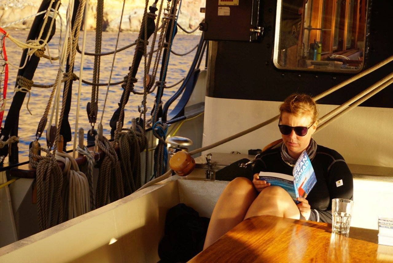 a woman reading a book on a boat.