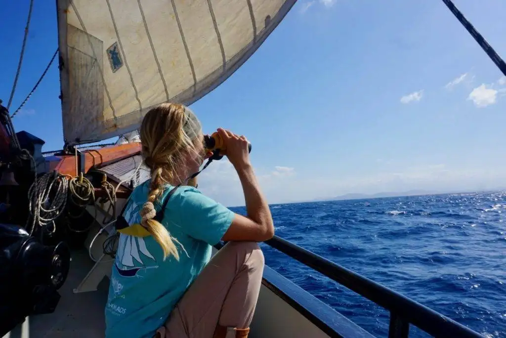 a woman is taking a picture of the ocean from the deck of a sailboat.
