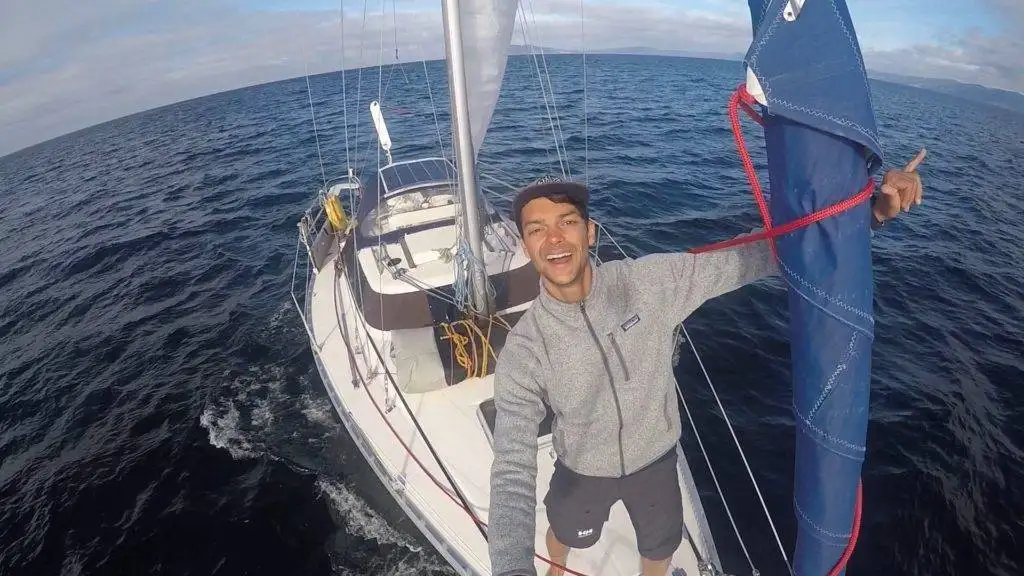 a man is standing on a sailboat with a sail in his hand.