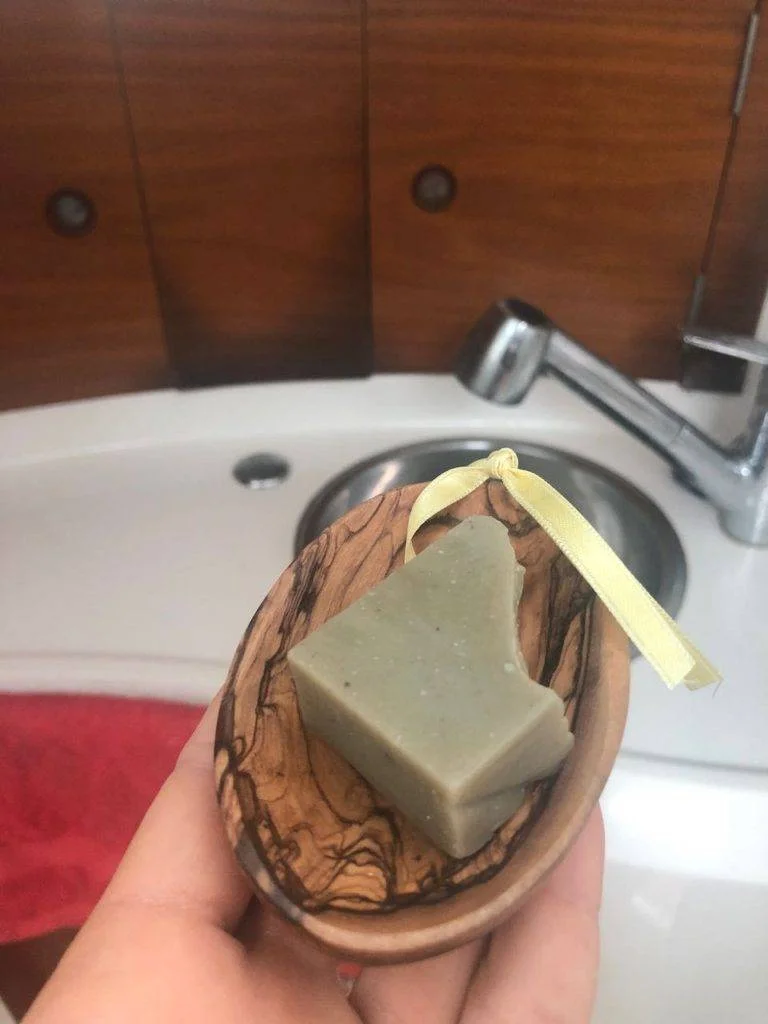 a person holding a soap bar in front of a sink.