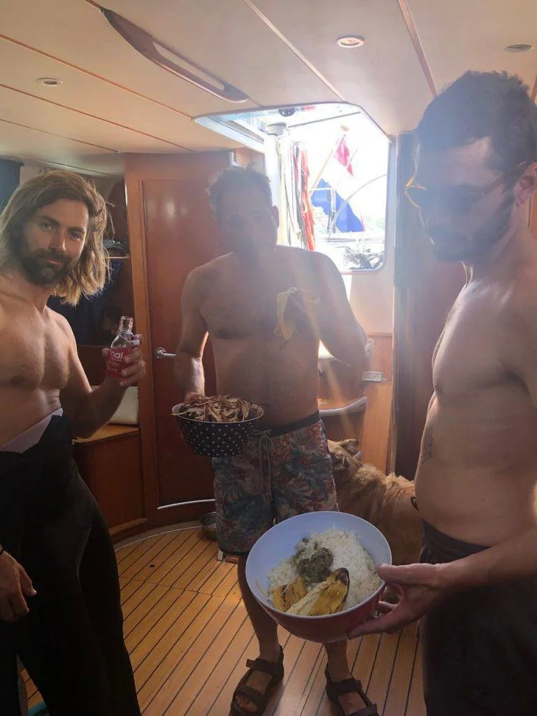 three men standing on a boat with a bowl of food.