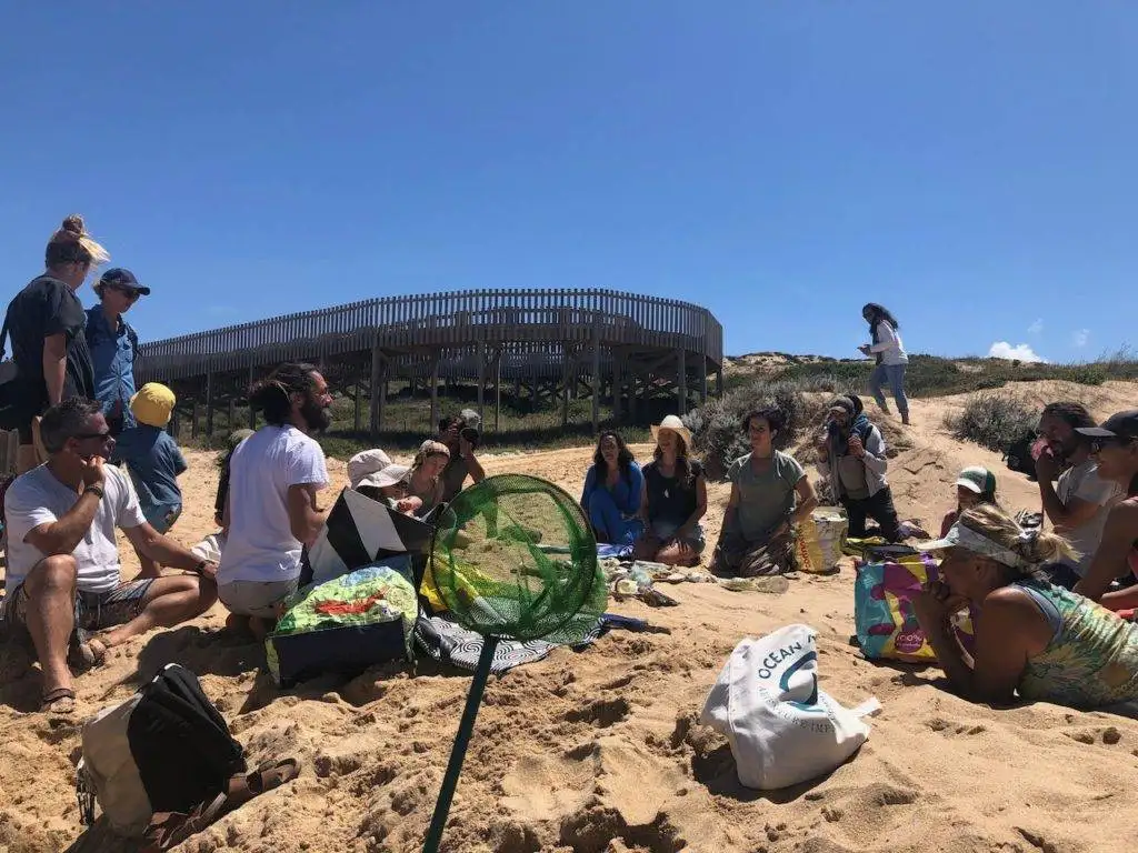 a group of people sitting in the sand on a beach.