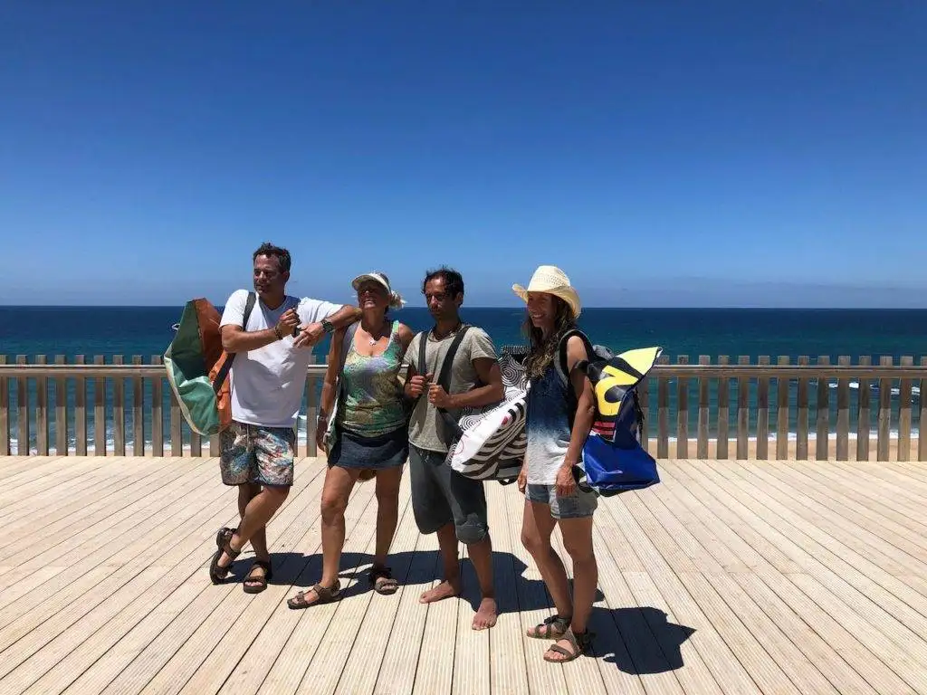 four people standing on a wooden deck with surfboards.