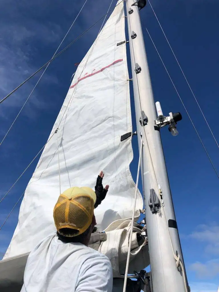 a man is working on the sail of a sailboat.