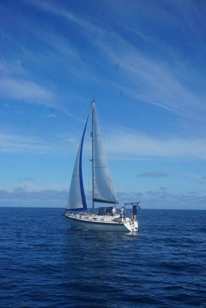 a sailboat in the open ocean with a blue sky.