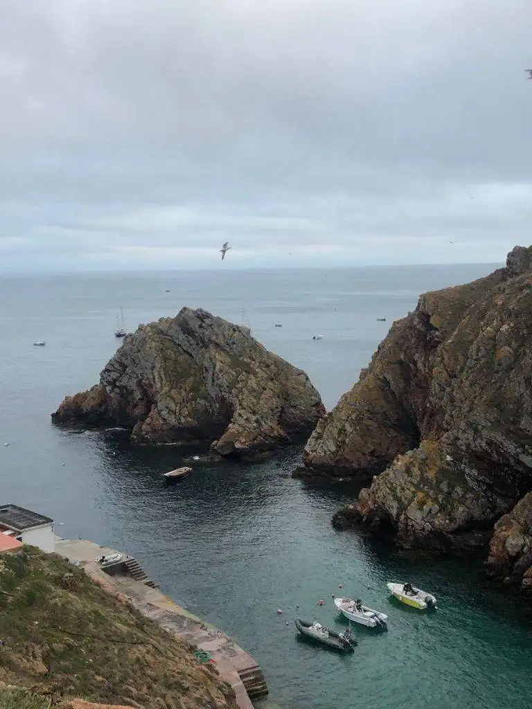 a group of boats are docked in the water near a rocky cliff.