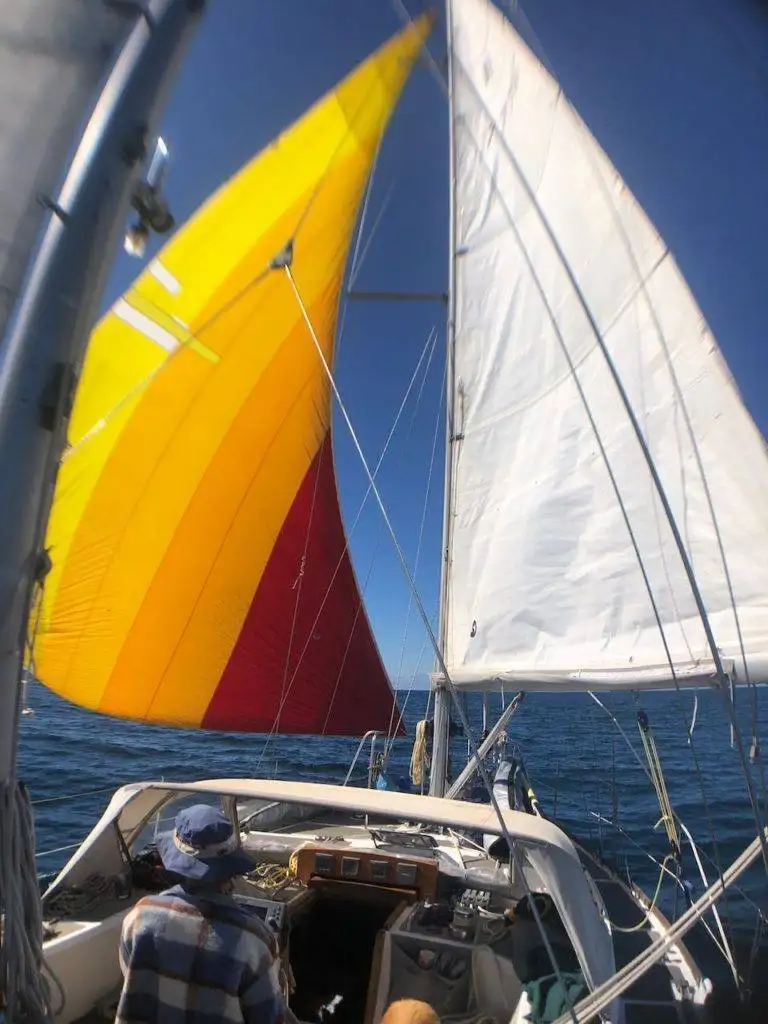a man on a sailboat with a yellow and red sail.
