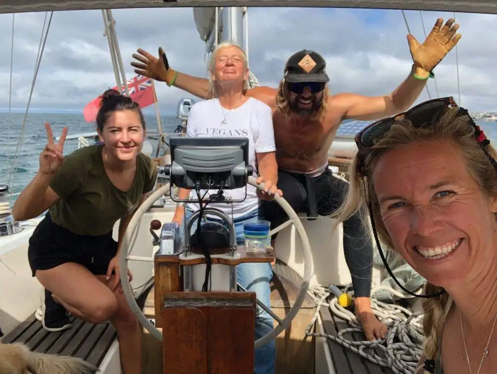 a group of people on a sailboat posing for a photo.