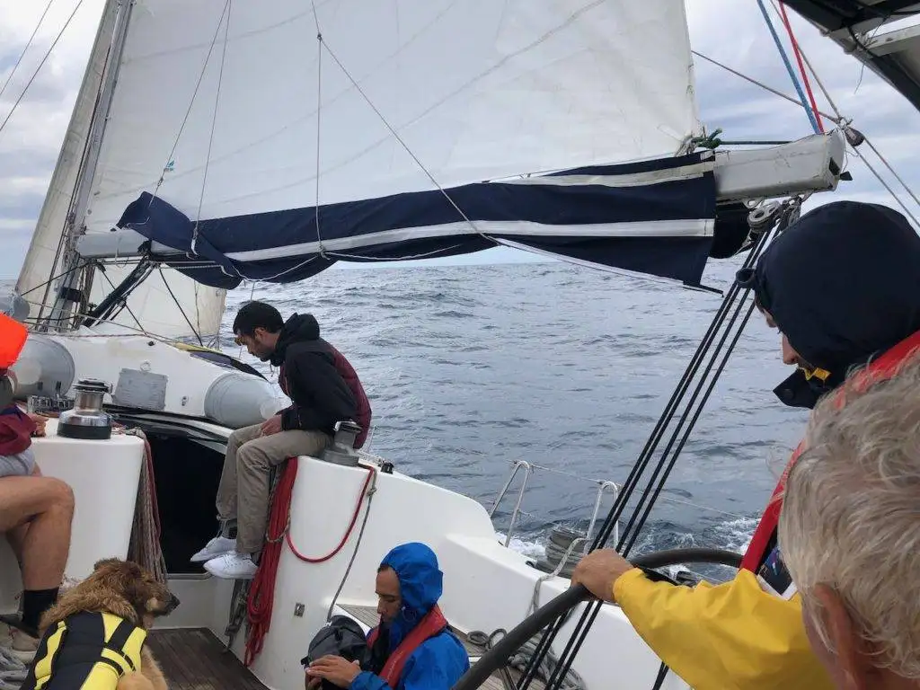 a group of people sitting on the deck of a sailboat.