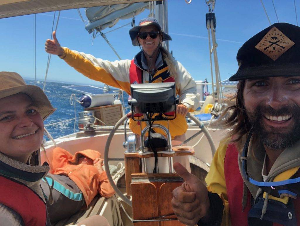 three people on a sailboat giving thumbs up.