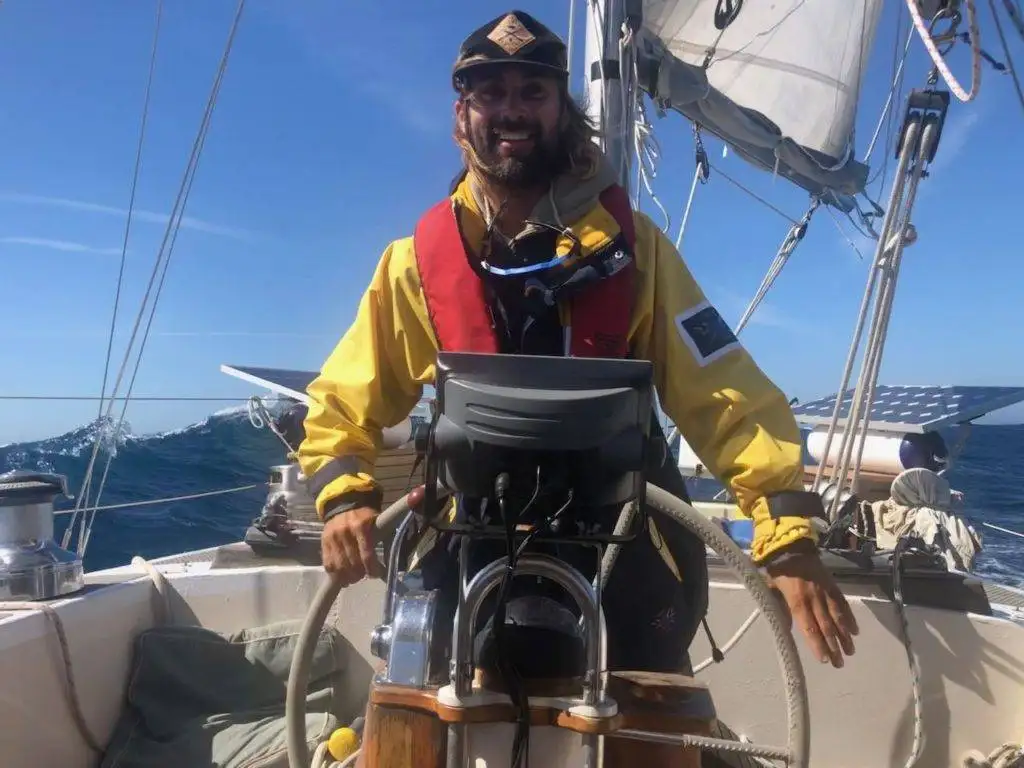 a man standing on the deck of a sailboat.