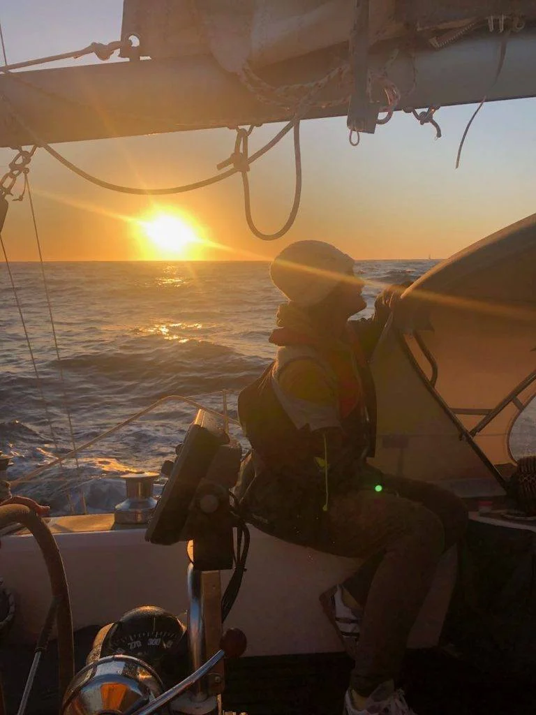 a person sitting on a sailboat at sunset.