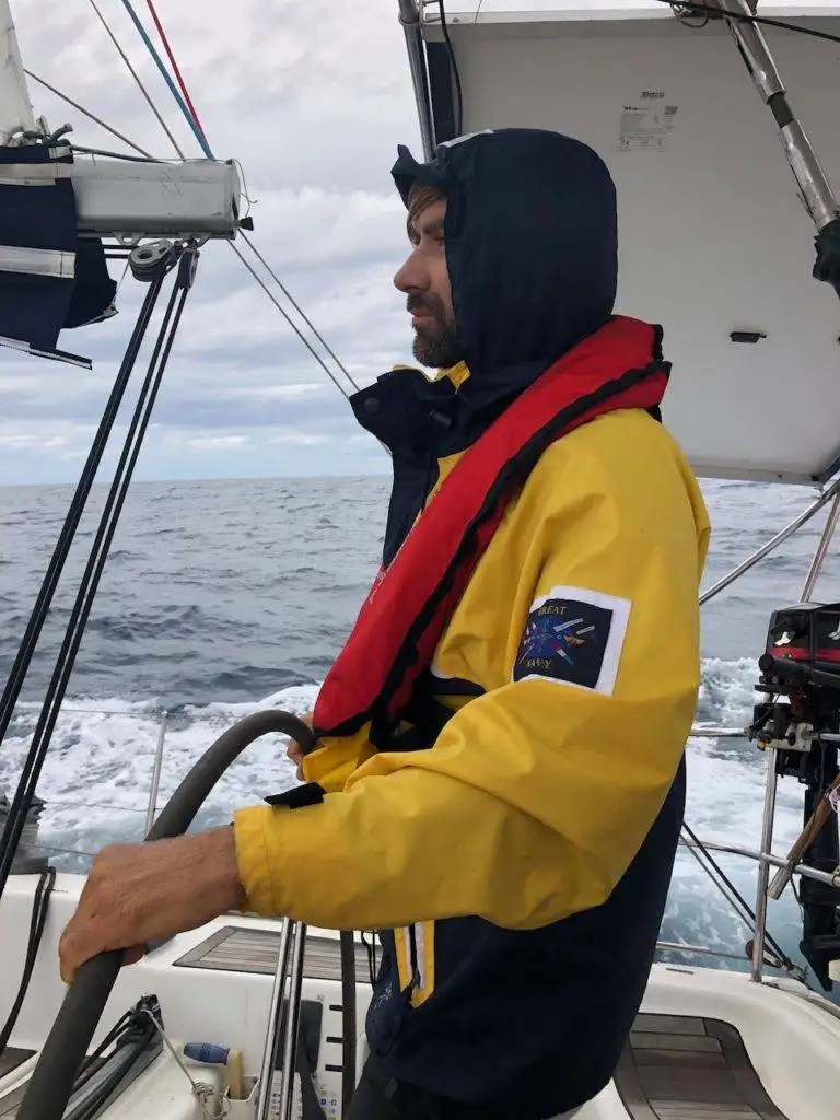 a man in a yellow jacket on a sailboat.