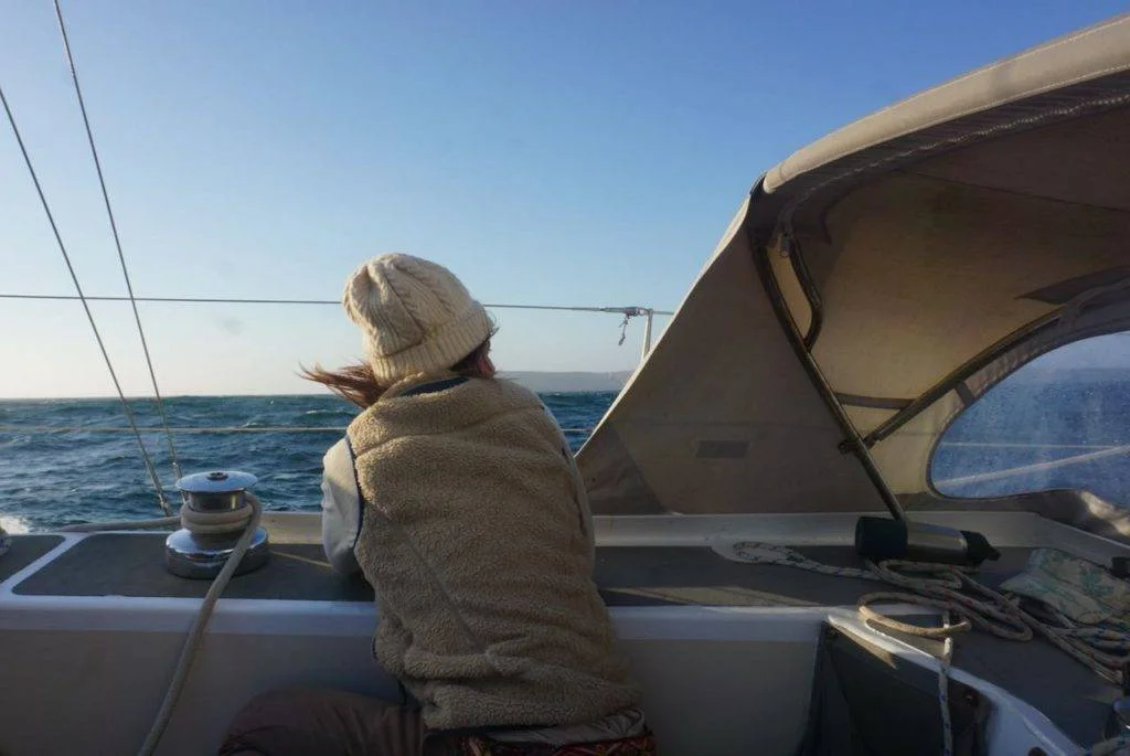 a woman on a sailboat looking out at the ocean.