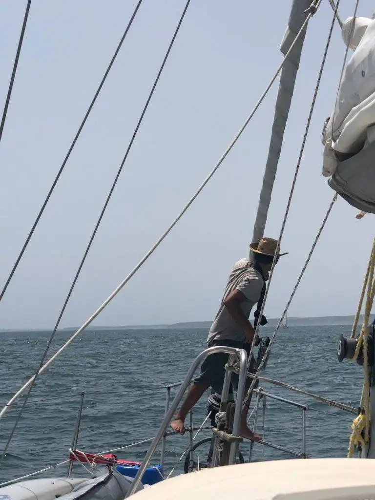 a man standing on the bow of a sailboat.