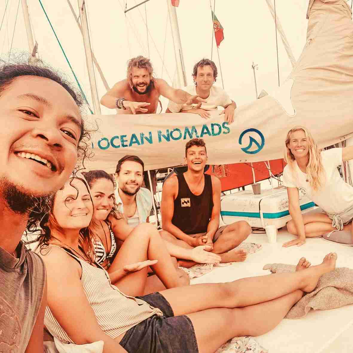 a group of people sitting on a boat with ocean nomads written on it.