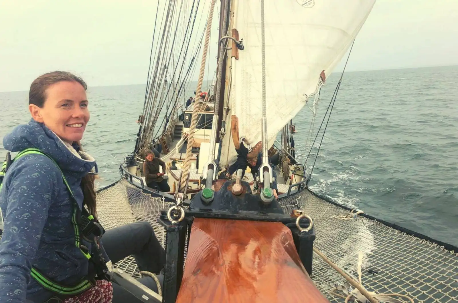 a woman sitting on the bow of a sailboat.