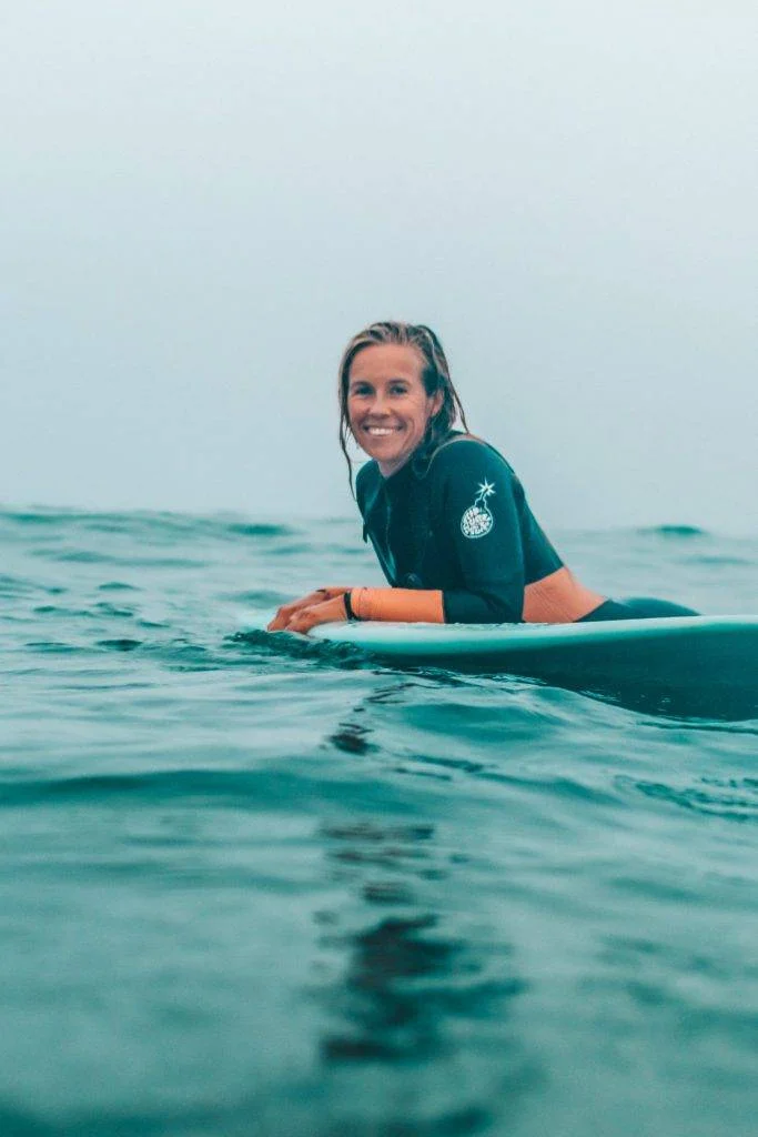 a woman in a wetsuit riding a surfboard in the Caribbean ocean.