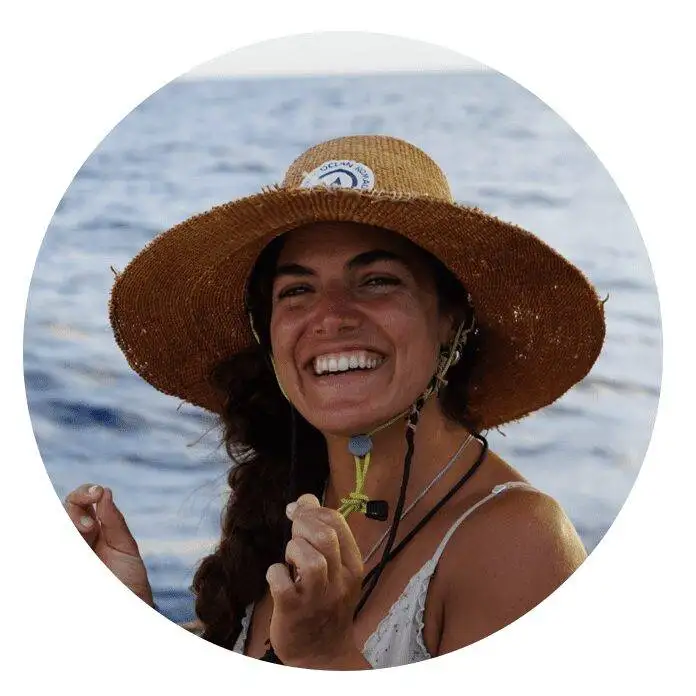 a smiling woman wearing a straw hat on a boat.