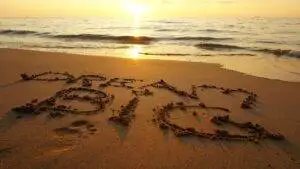 The word dream big written in the sand at sunset.