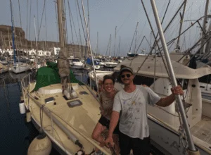A sailing crew consisting of two people standing on a boat.