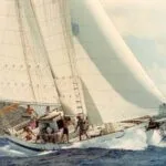 Sailing yacht heeling in strong wind with crew on deck, living their ocean dream.