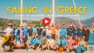 A group of people poses on a dock in front of sailboats, with "SAILING IN GREECE: A film on adventure, impact, and community" overlayed. Don't miss this new film by Ocean Nomads, premiering December 20.