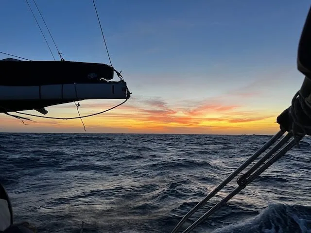 Sailboat on the ocean at dusk, as a vibrant sunset paints the sky near Cape Verde.