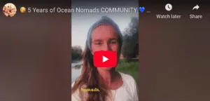 A woman with long hair and a headband speaks outdoors near water and trees. The word “OCEAN NOMADS COMMUNITY” appears in yellow text at the bottom, highlighting a special community anniversary celebration.